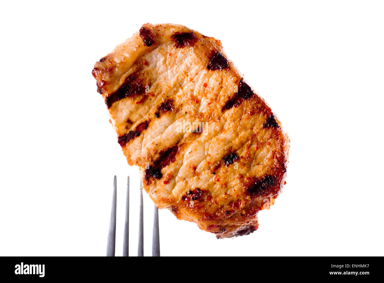 Grilled pork chop without bone on a fork. Spiced with dried chili and paprika. Stock Photo