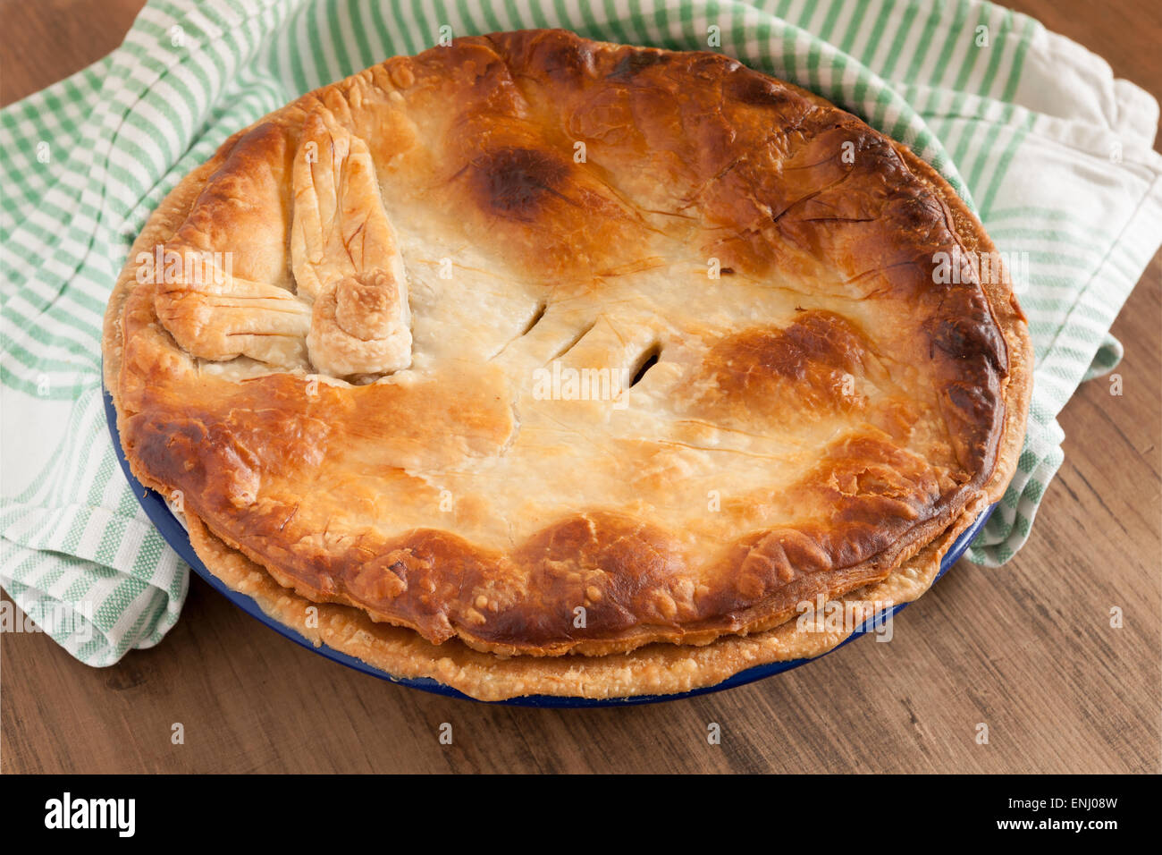 Home baked pie with a golden puff pastry crust baked in enamelware pie dish can be used for savory or sweet fillings Stock Photo