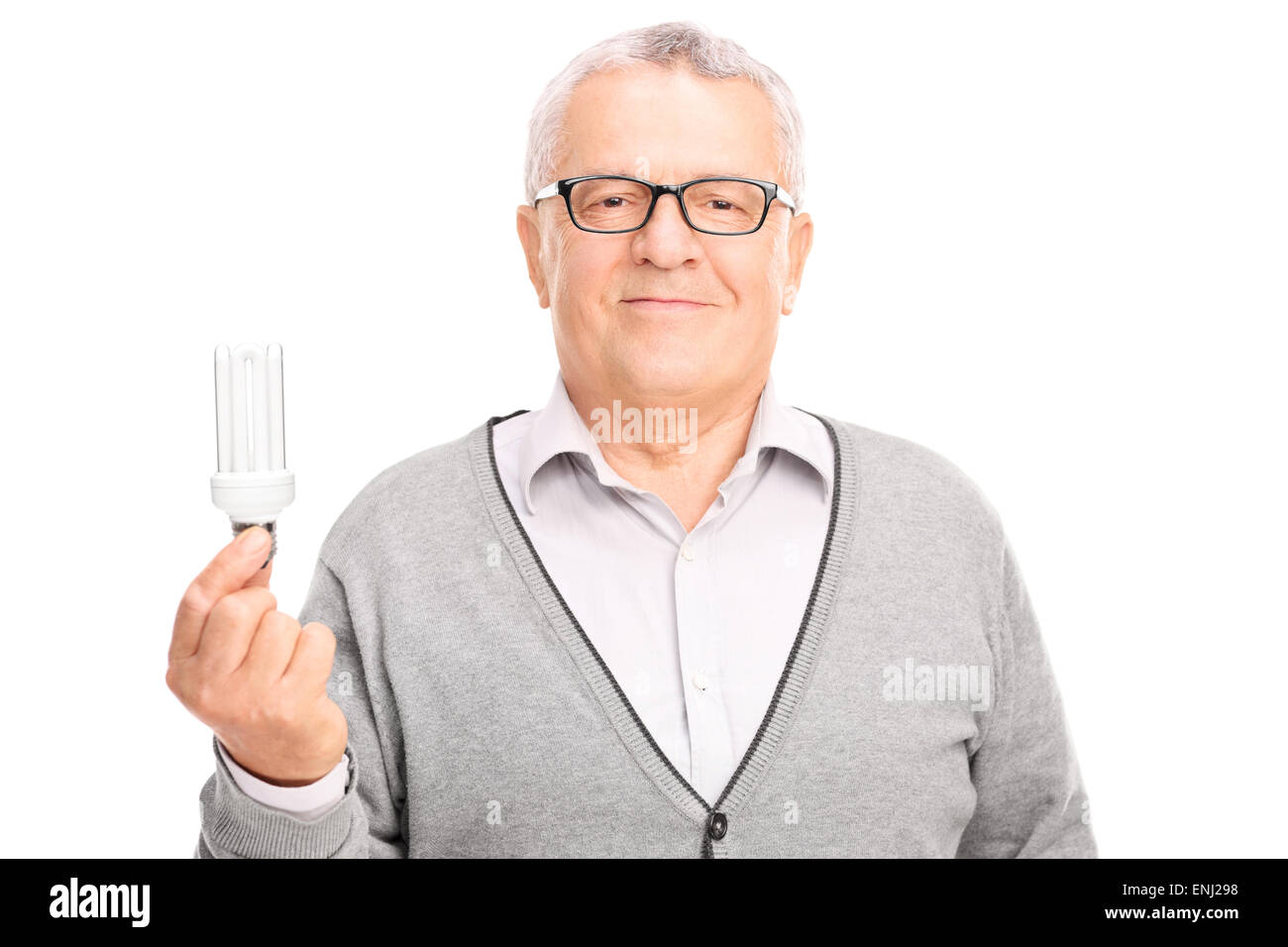 Close-up on a senior gentleman holding an energy efficient light bulb and looking at the camera isolated on white background Stock Photo