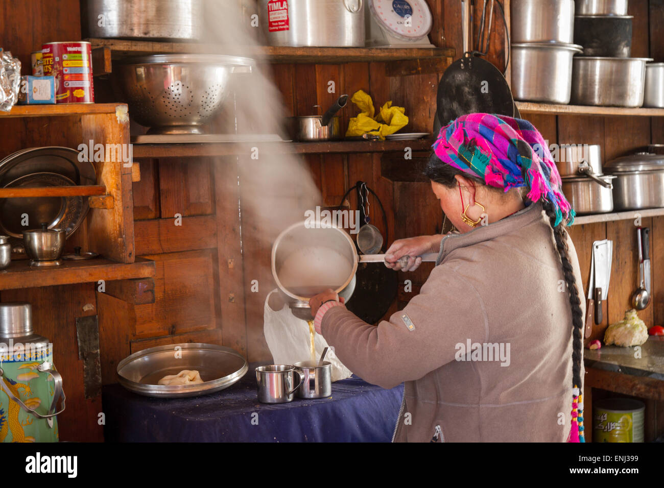 Friendly Tibetan woman pouring tea in a guesthouse in Langtang Village, Langtang, Nepal Stock Photo
