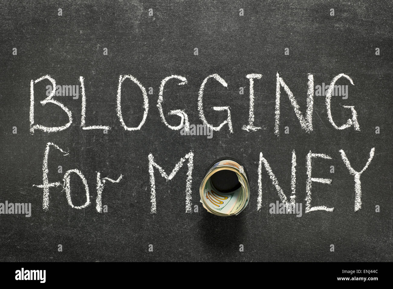 blogging for money phrase handwritten on blackboard with money roll instead of O Stock Photo