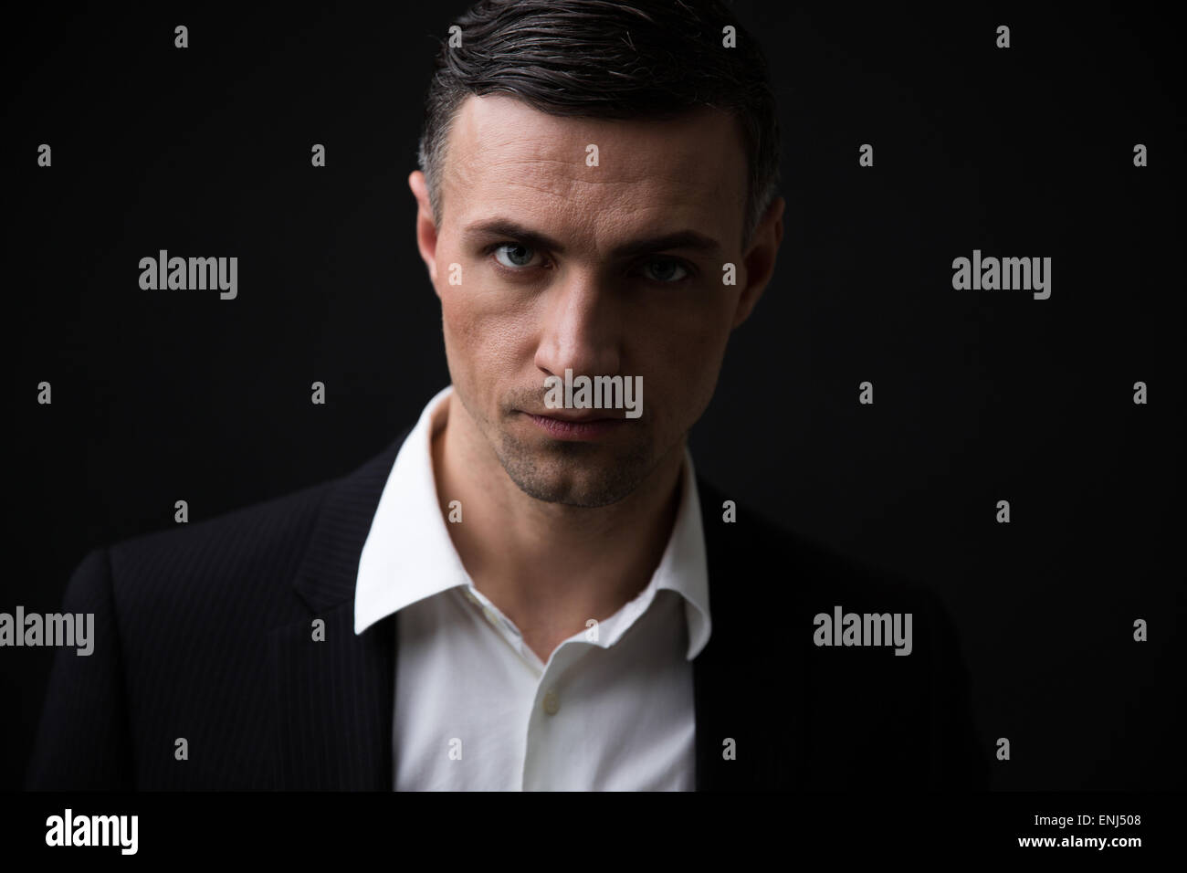 Handsome businessman in formal wear looking at camera over black ...