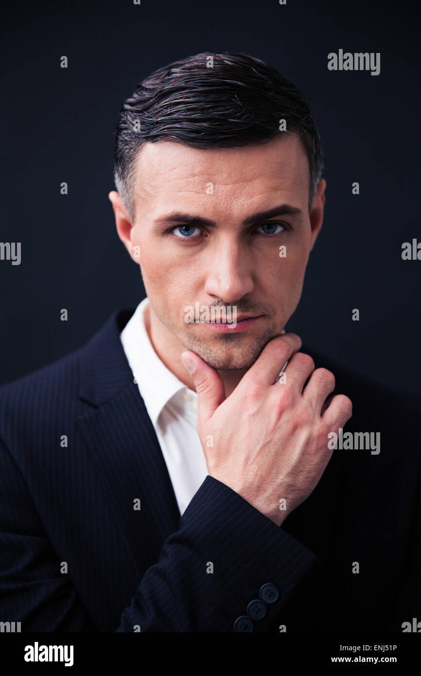 Handsome businessman in formal wear looking at camera over black ...