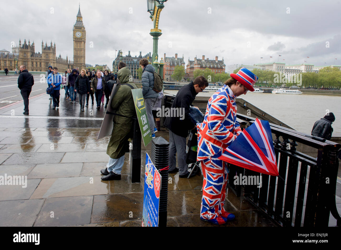 High winds and wet weather herald an uncertain week in the Britain less than 24 hours before the UK's general election. Unlikely prospects for a majority government by the end of the week means stormy deals between political parties and discontent with voters. A tourist leaflet man dressed in union jacks hands out details for a nearby fish and chip business, opposite the Palace of Westminster on Westminster Bridge. Stock Photo