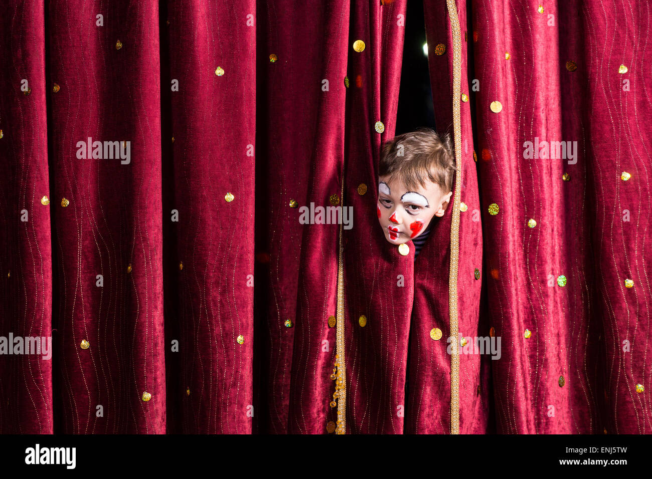 Impatient young boy actor wearing colorful red face paint peeking out ...
