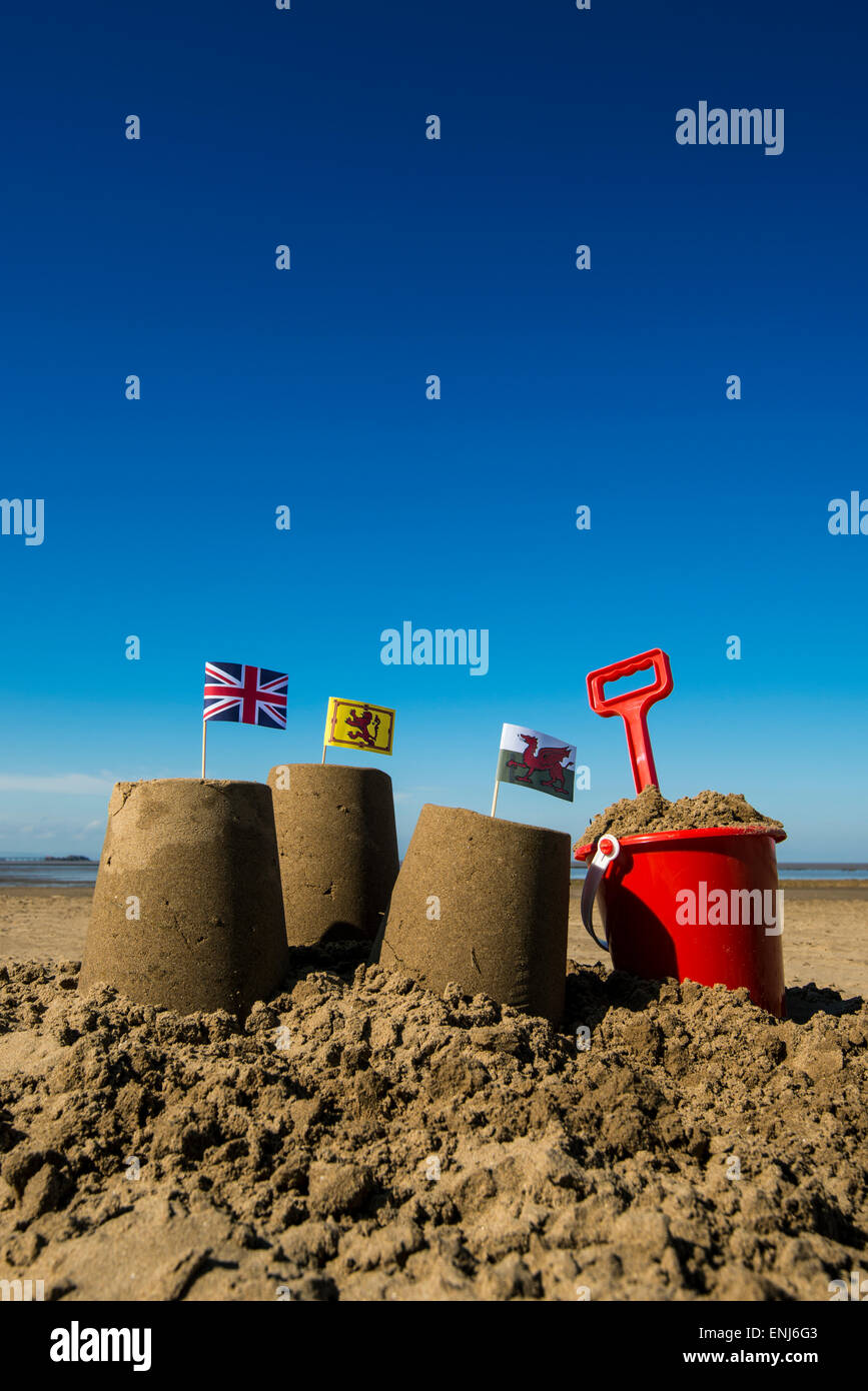 Three sandcastles with flags and a red bucket and spade Stock Photo