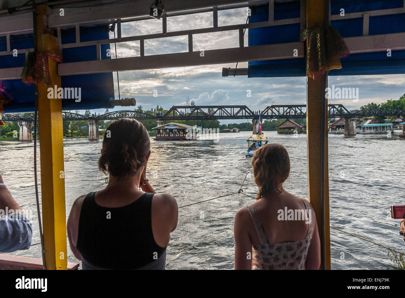 Tourists on a boat floating towards the bridge over the river Kwai. Kanchanaburi. Thailand Stock Photo