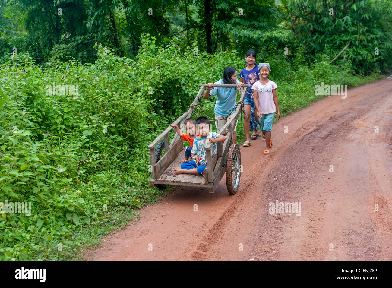 Thai children pushing a cart with younger kids inside. Thailand Stock Photo
