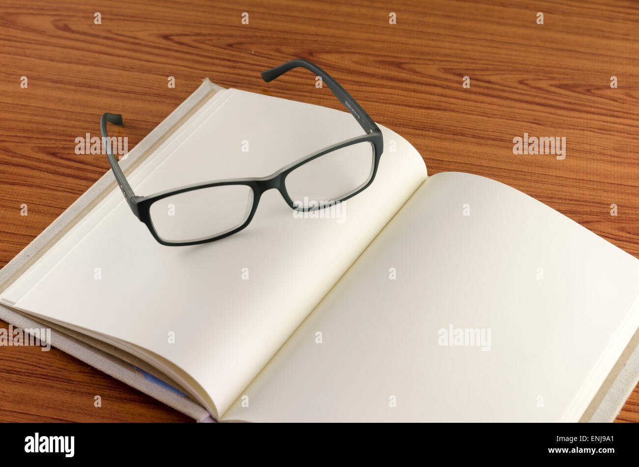 close up glass with notebook on wood background Stock Photo - Alamy