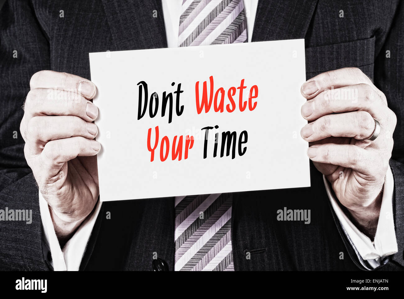A businessman holding a card with the words,  Don't Waste Your Time! written on it. Stock Photo