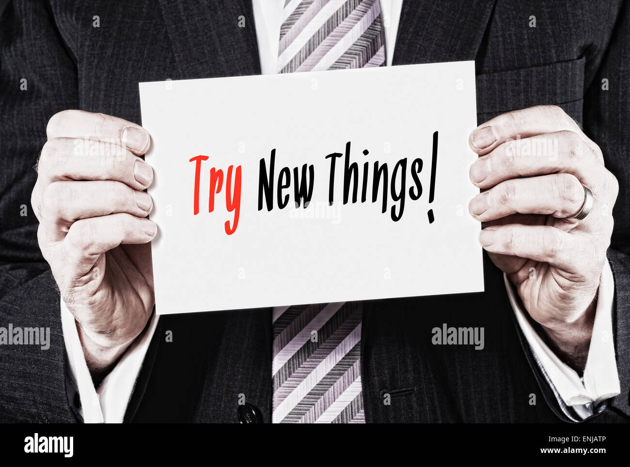 A businessman holding a business card with the words, Try New Things, written on it. Stock Photo