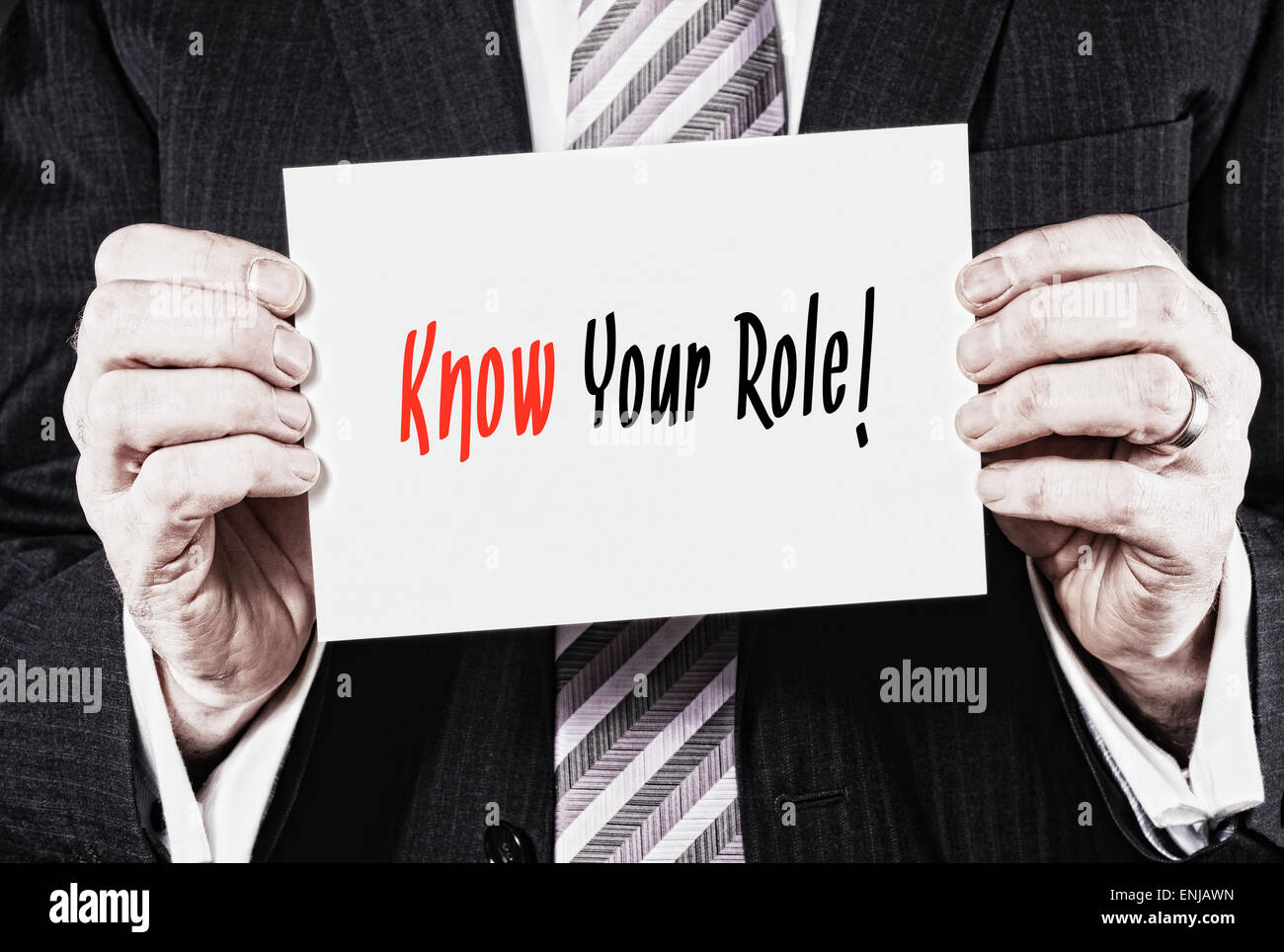 A businessman holding a card with the words, Know Your Role, written on it. Stock Photo
