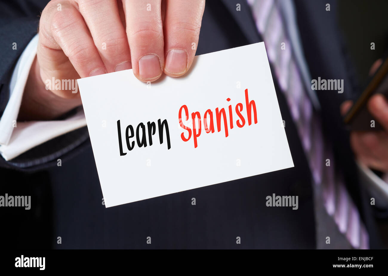 A businessman holding a business card with the words, Learn Spanish, written on it. Stock Photo