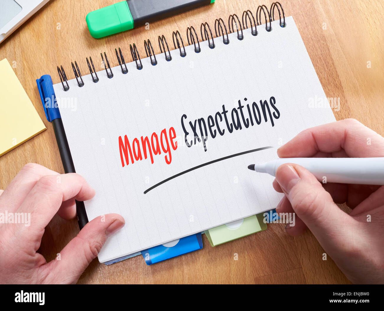 A businessman writing the words, Manage Expectations, on a note pad. Stock Photo
