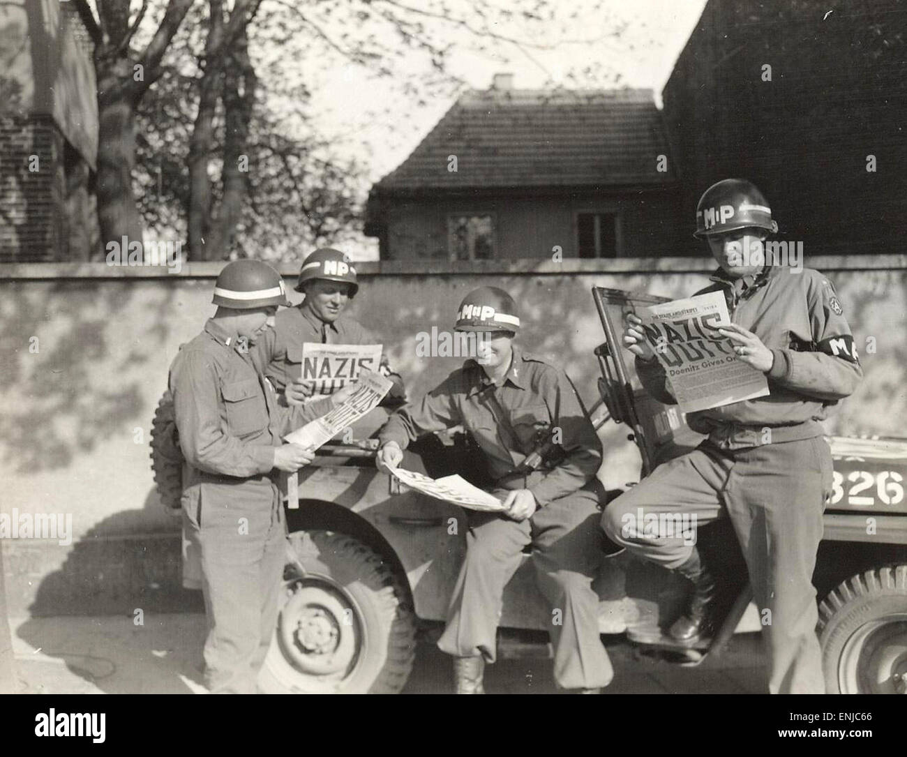 US military policemen read about the German surrender in the newspaper Stars and Stripes. 1945 Stock Photo