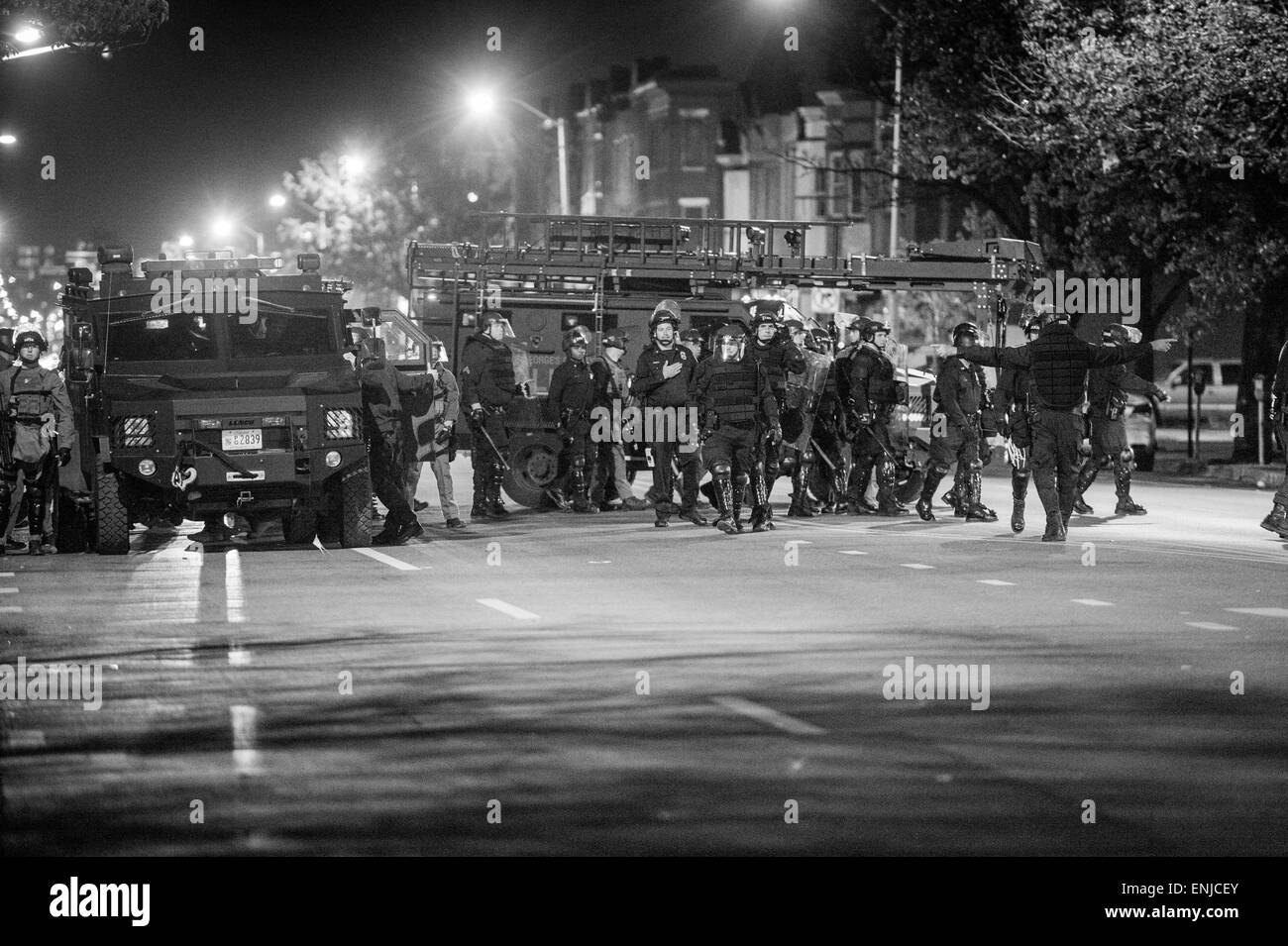 After the cop related death of Freddie Gray, West Baltimore erupted in riots and protests attempting to bring attention to police brutality within the Baltimore Police Department. Here, along with a group of protesters convened at Pennsylvania and North Avenue in West Baltimore, riot police wait armed to enforce the 10pm curfew. Stock Photo
