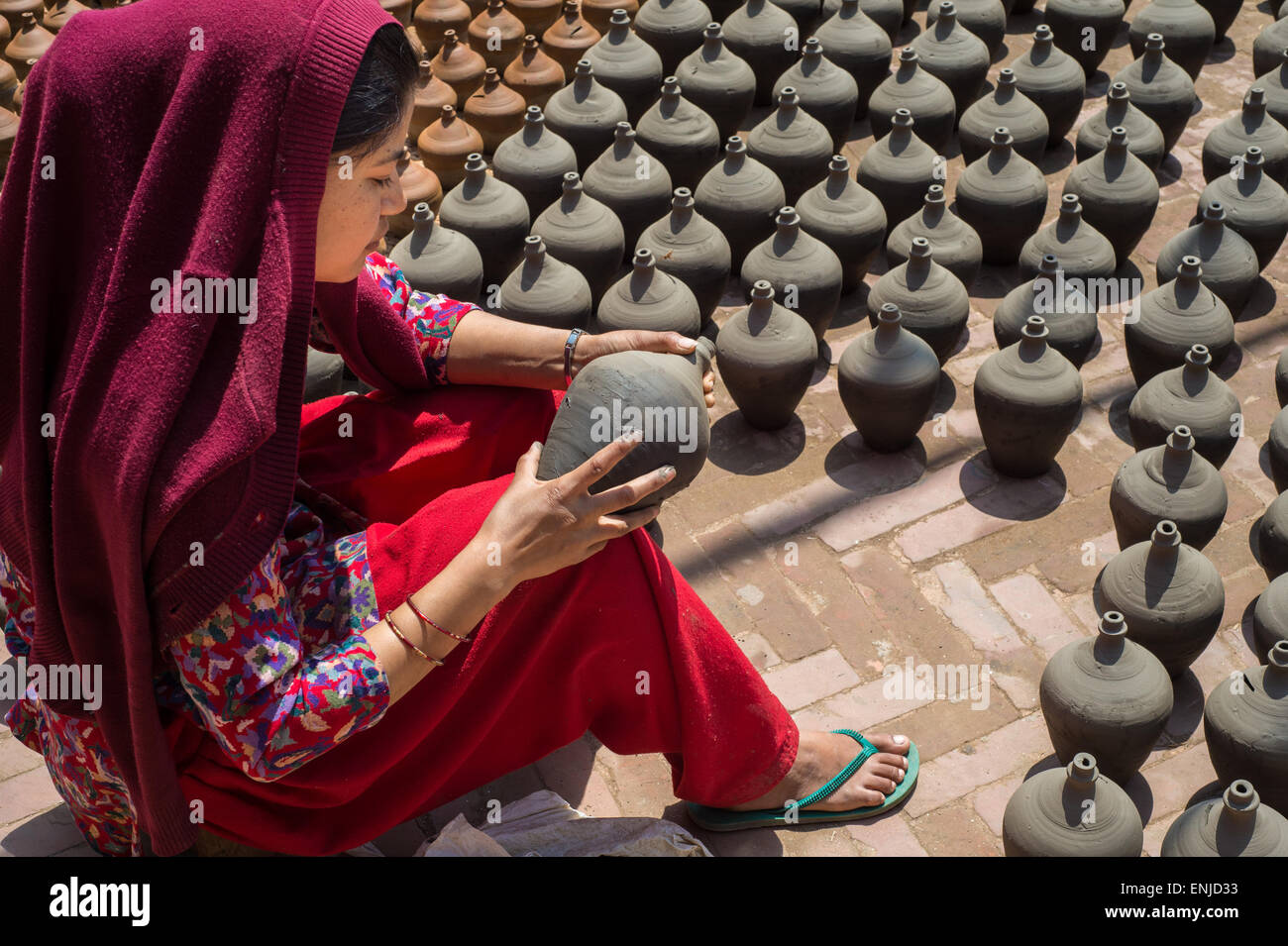 Bhaktapur, Nepal - 20 march 2015: Woman placing potteries to dry on Pottery Square. Stock Photo
