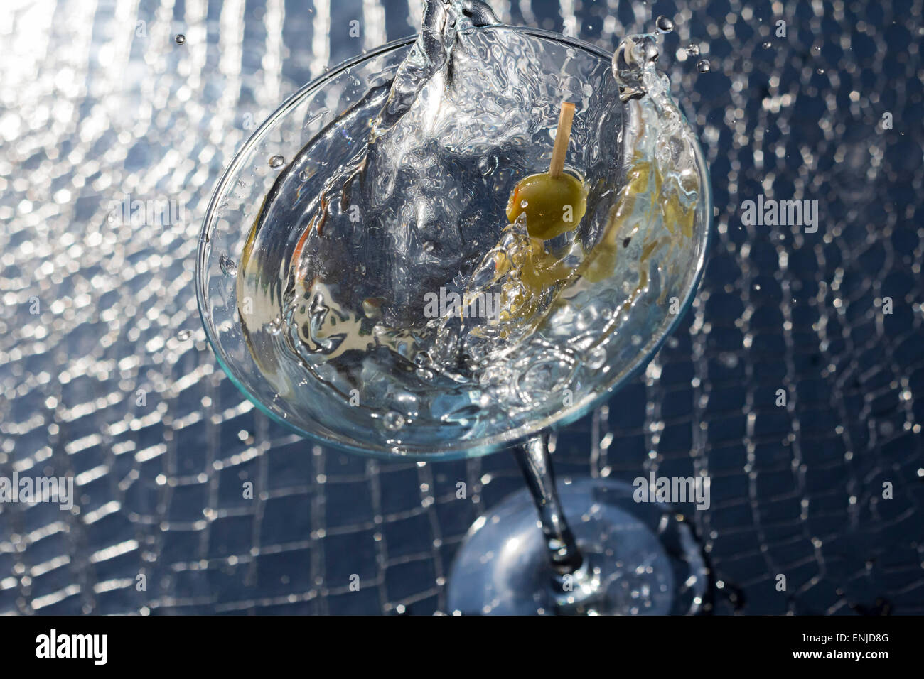 Splashing dirty martini garnished with green olives on toothpick Stock Photo