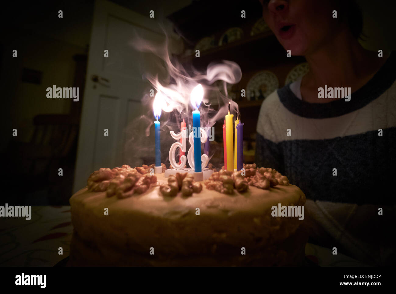 A woman blowing out candles on her birthday cake. Instagram type styling applied some light grain added. Stock Photo