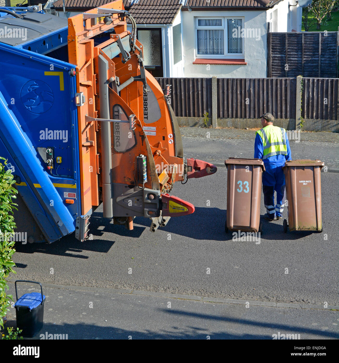 Back view from above high visibility dustman rear of refuse collection truck pulling two wheelie bins in residential street Brentwood Essex England UK Stock Photo