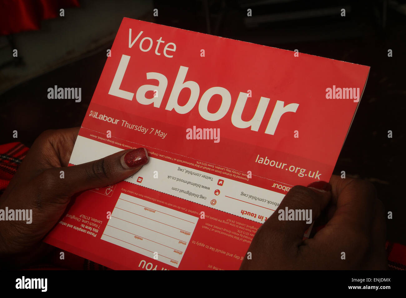 London, UK. 6 May 2015. An immigrant voter reads a Labour election flyer. Voters in the UK prepare to go to the polls on Thursday 7 May, in an election seen as one of the closest-fought in years. Britain's two-party system appears under severe threat, with the distinct prospect that between them Labour and the Conservatives will struggle to gain two-thirds of the votes cast. Compare that with their near 90% vote share just 50 years ago. Credit: David Mbiyu/ Alamy Live News Stock Photo
