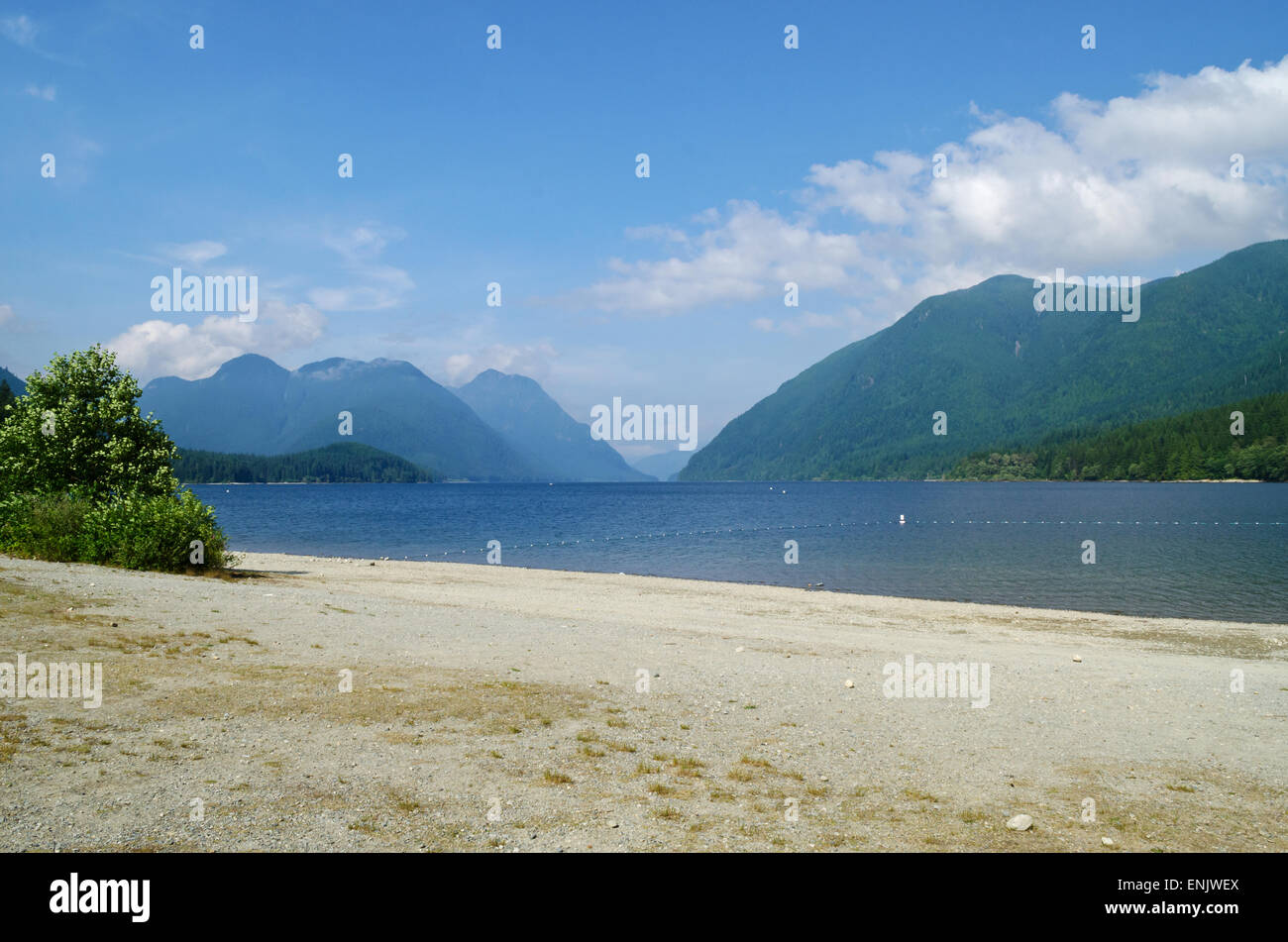 The sandy beach of Alouette Lake in Golden Ears Provincial Park.  Blue water and mountains on a sunny day.  In Maple Ridge, BC. Stock Photo