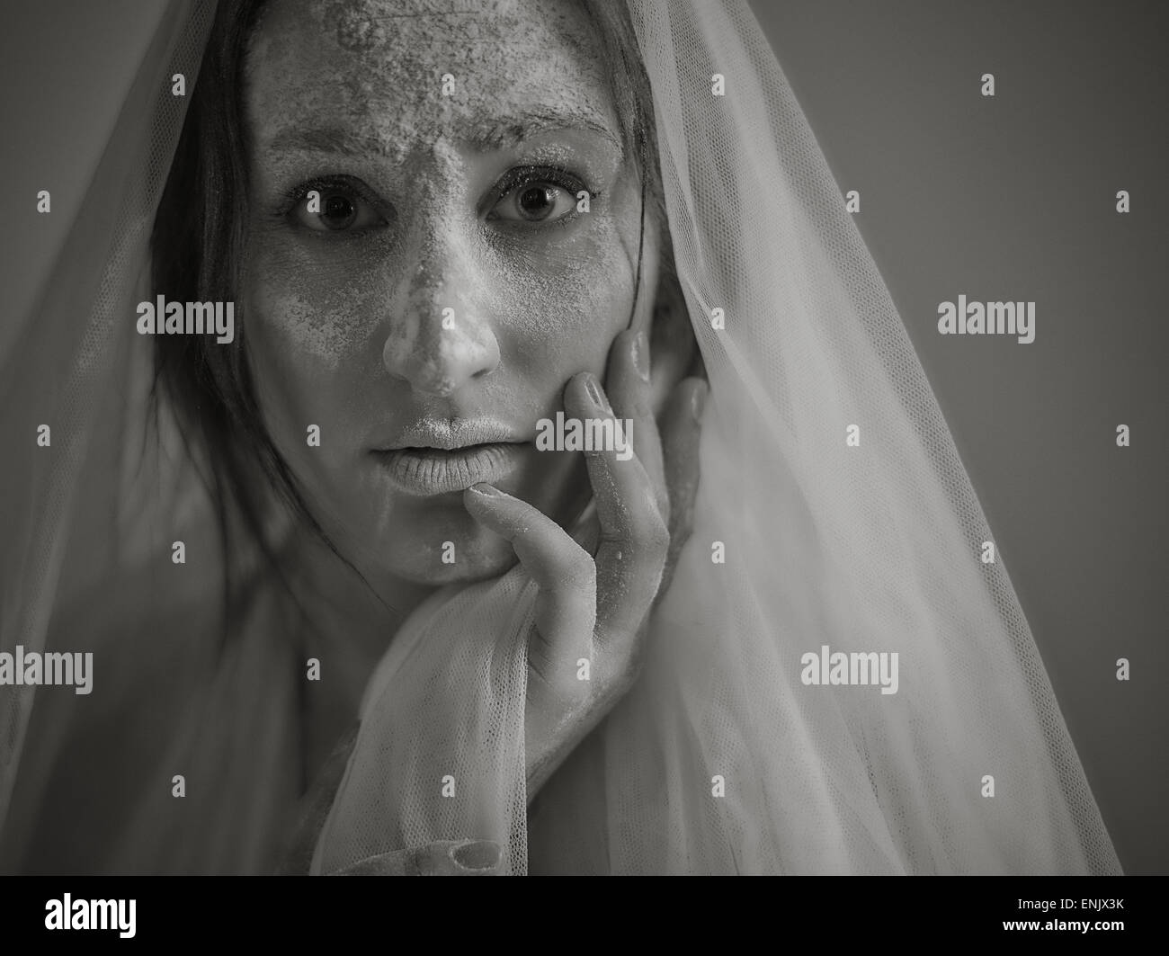 Close up woman face and ashes, she wearing white canvas, tinted black and white image, intentional noise added Stock Photo