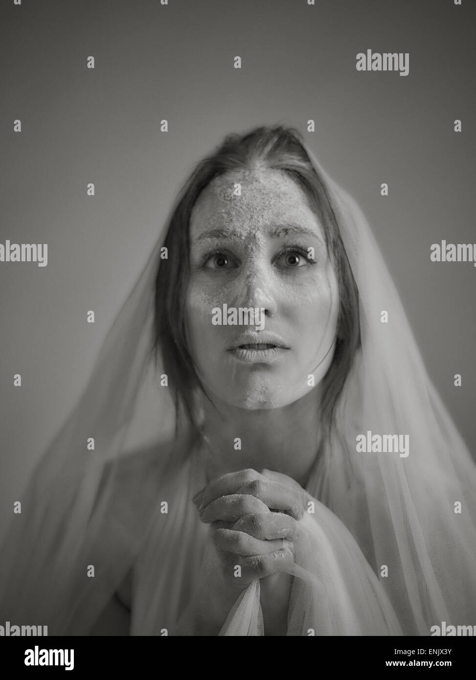 Close up woman face and ashes, she wearing white canvas and she praying, tinted black and white image, intentional noise added Stock Photo