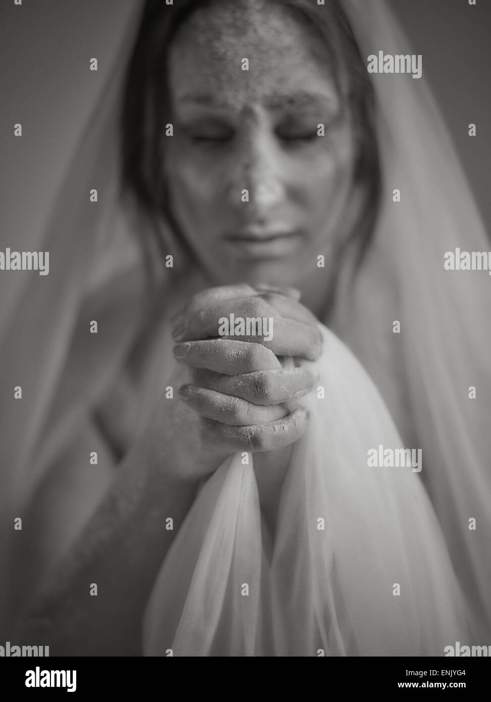 Close up woman face and ashes, she wearing white canvas and she praying, tinted black and white image, intentional noise added Stock Photo