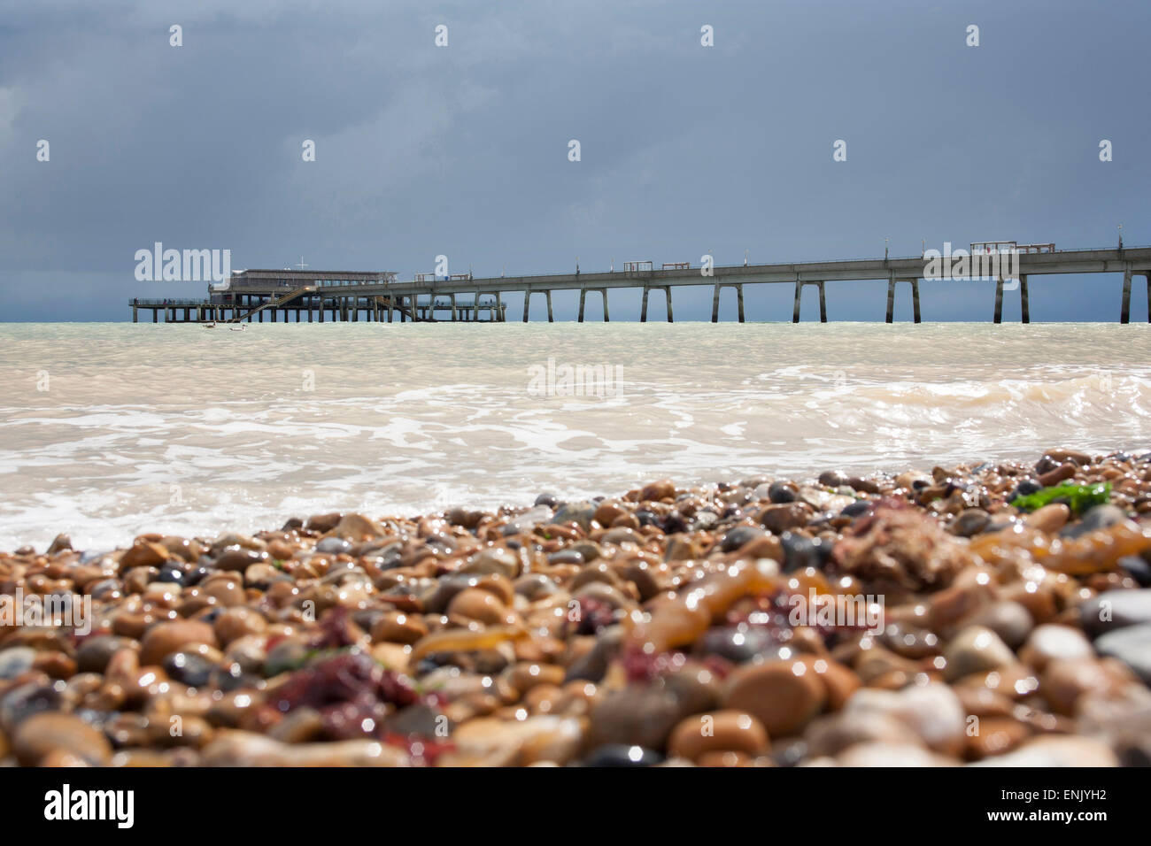 Deal beach in Kent showing pier, shingle and sea against a dark grey cloudy rainy sky Stock Photo