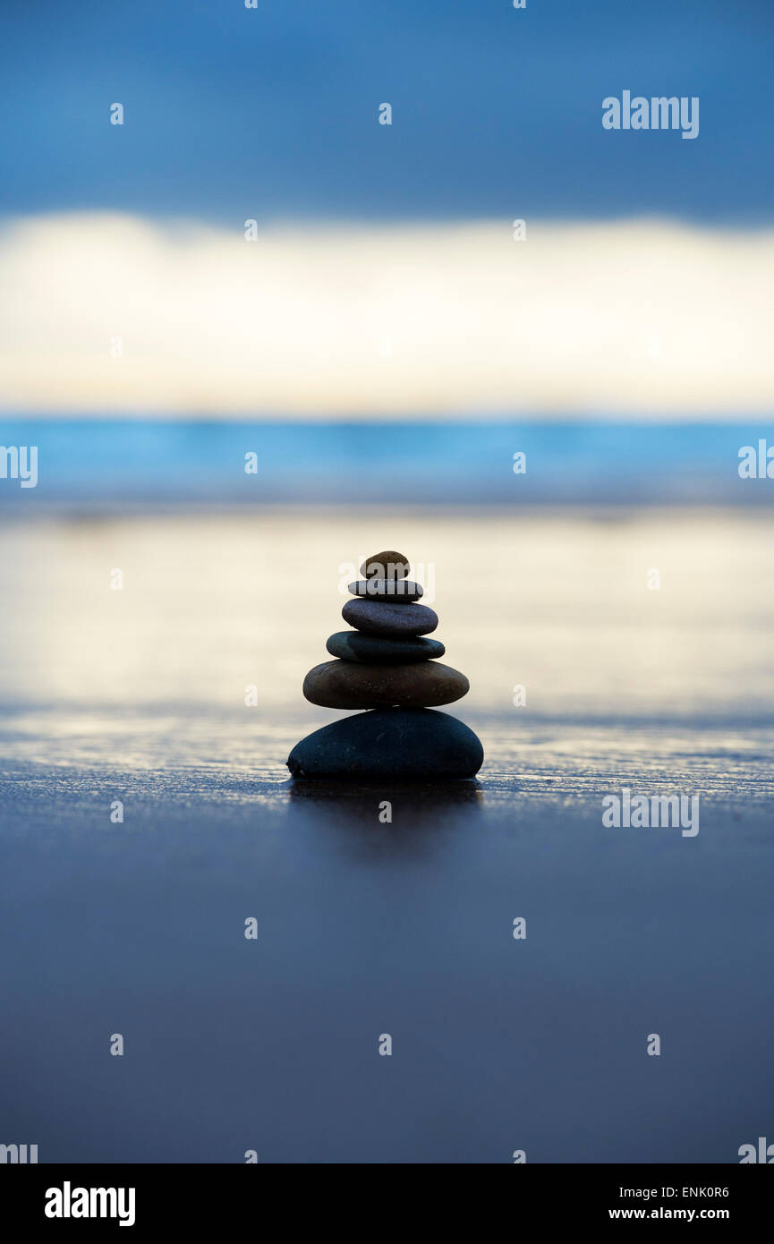 Pebbles balancing on a stormy beach in the early morning light. Selective focus Stock Photo