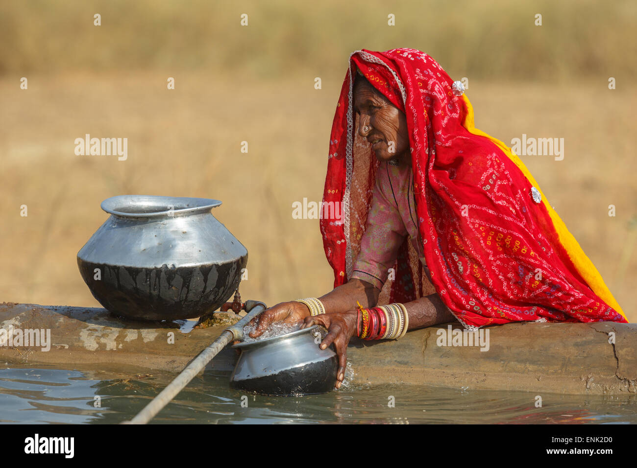 PUSHKAR,INDIA - November 3,2014 : Unidentified women draw water form the well and take it to her tent in desert. Stock Photo