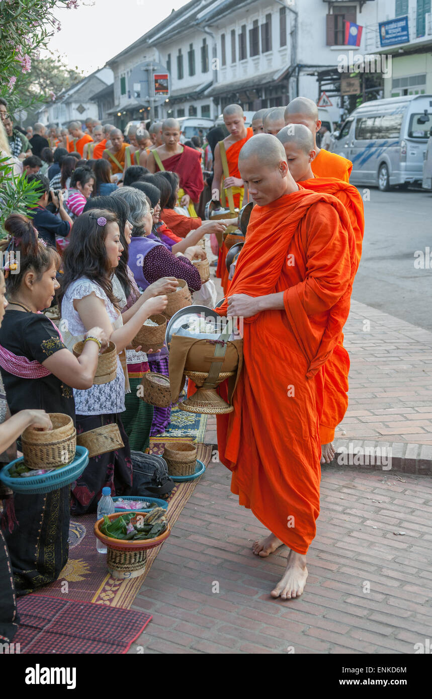 LUANG PRABANG, LAOS - FEBRUARY 19, 2011: unidentified monks walk to collect alms and offerings on February 19, 2011. Stock Photo