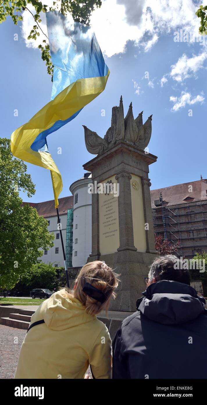 Torgau, Germany. 07th May, 2015. A woman holds a Ukrainian flag behind the Soviet memorial in Torgau, Germany, 07 May 2015. Members and sympathizers of the Russian motorcycle club 'Nachtwoelfe' (lit. Night wolves) are expected in Torgau on Thursday afternoon. The group is on a tour from Moscow to Berlin. They want to arrive in the German capital on 09 May 2015 - when Russia observes the day of victory over Hitler's Germany. Photo: HENDRIK SCHMIDT/dpa/Alamy Live News Stock Photo