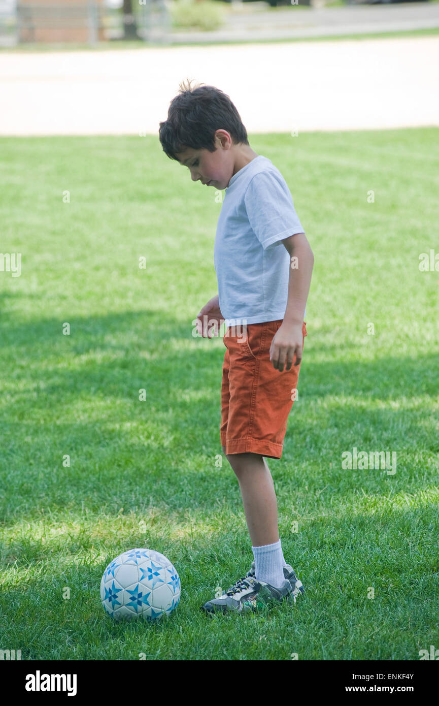Seven year old boy kicks soccer ball at summer camp. (Boy kicking ball