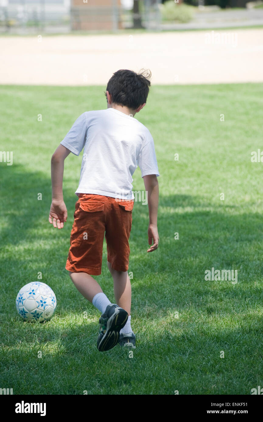 Seven year old boy kicks soccer ball at summer camp. (Boy kicking ball