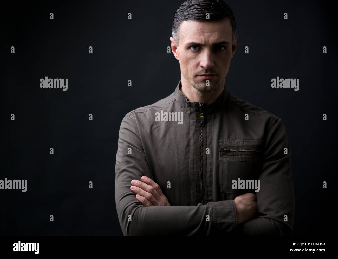 Confident young man with arms folded standing over black background ...
