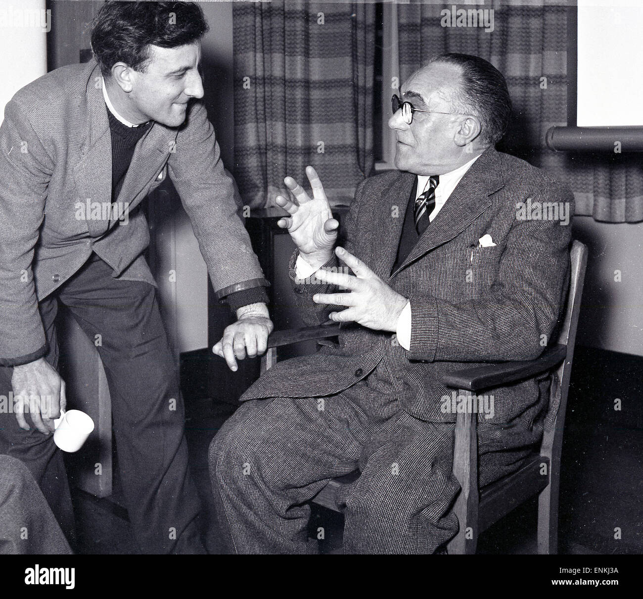 Historical, 1950s, a male actor in discussion with the theatre director sitting offset in a wooden chair, Oxford, England, UK. Stock Photo
