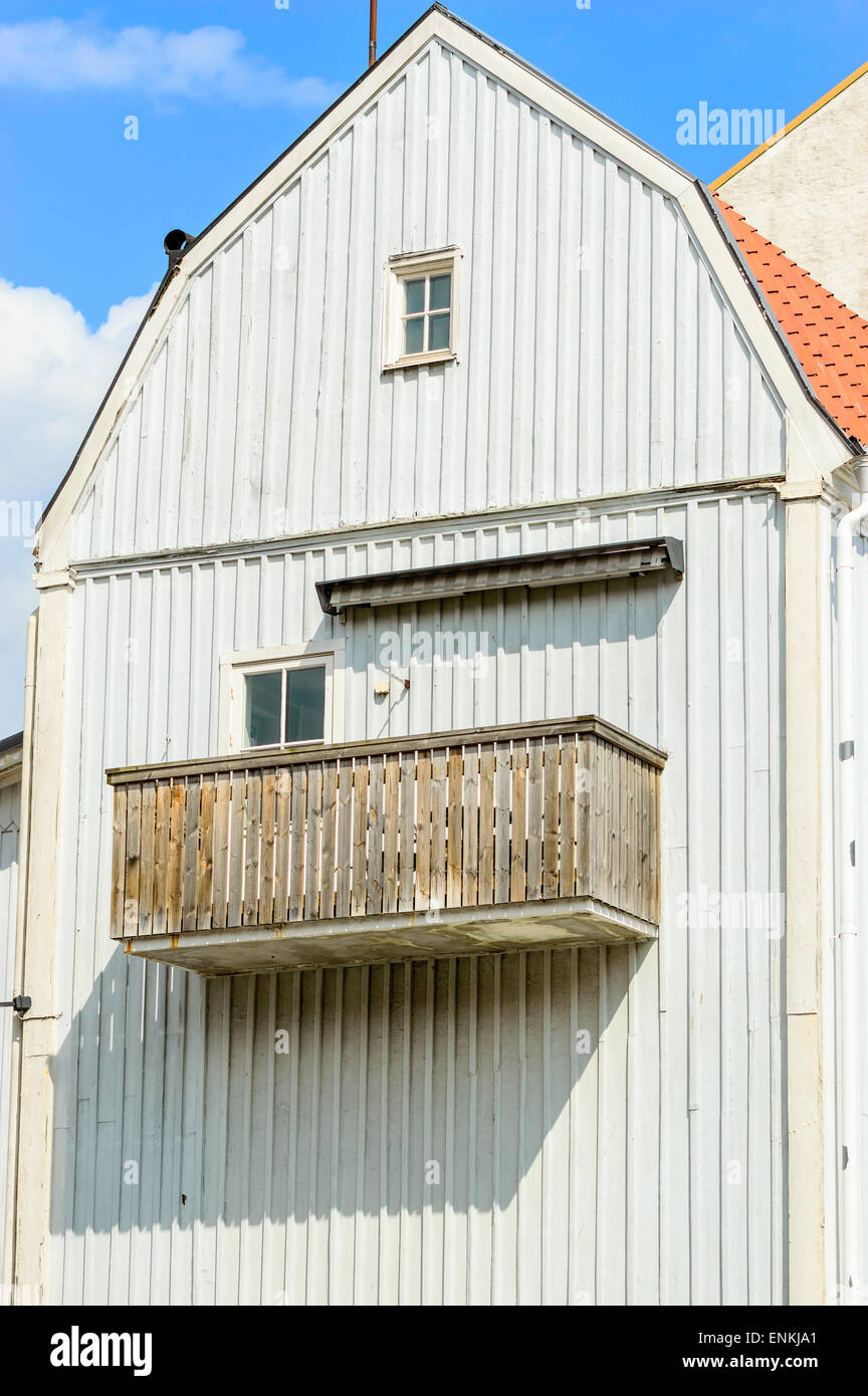 Unpainted old balcony on grey wooden house with small windows. Stock Photo