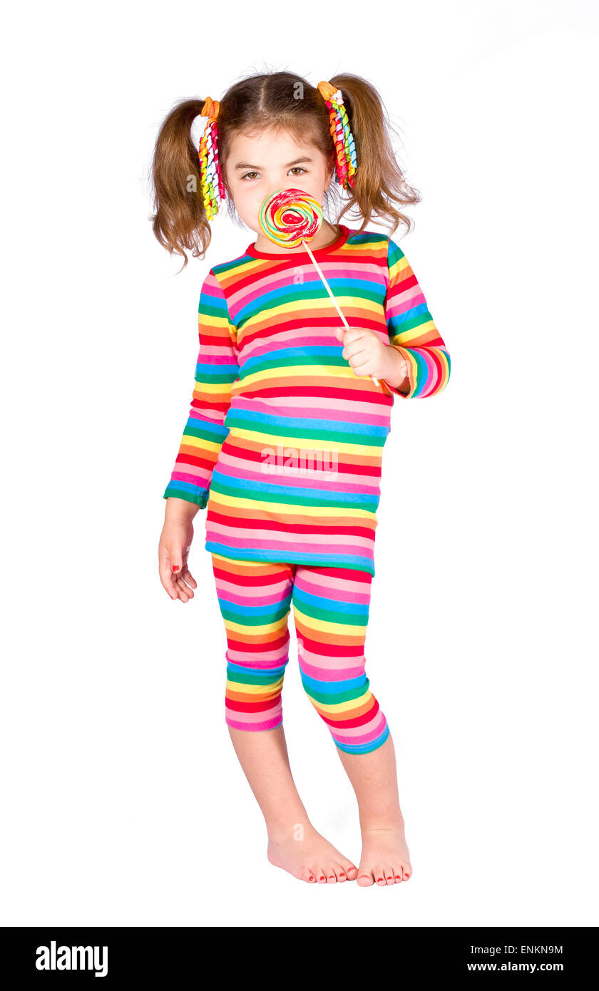 Girl in bright striped dress is holding candy on stick near the face Stock Photo