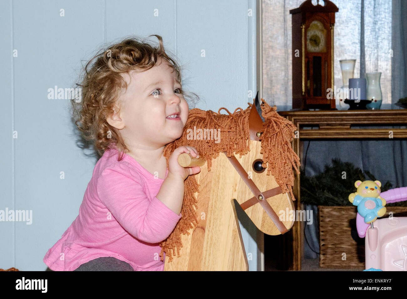 A 10 month old baby girl laughs while riding her wooden rocking horse. Stock Photo