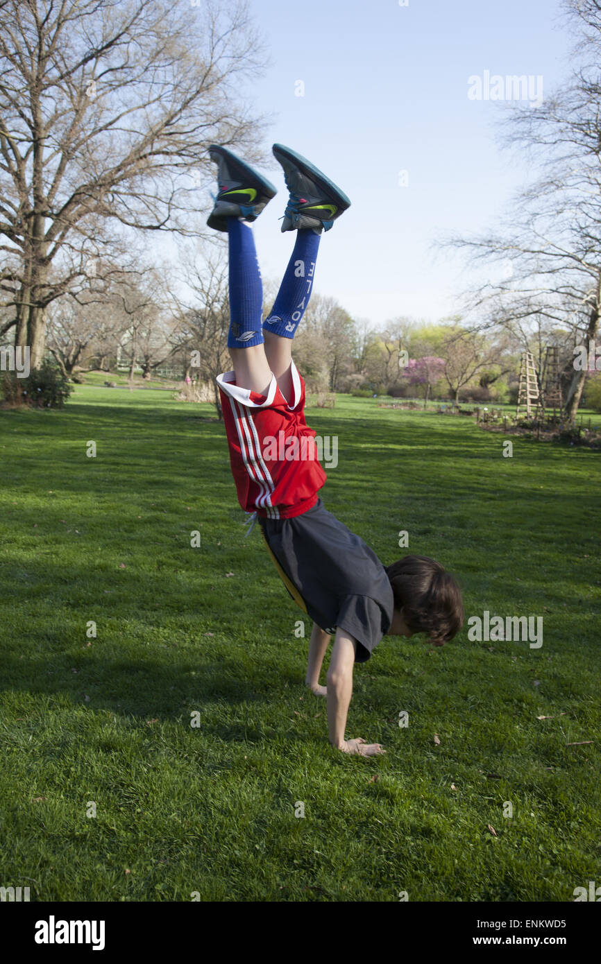 Boy does a handstand at the park. Stock Photo