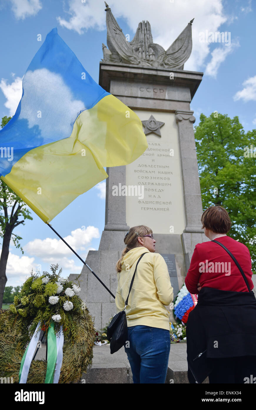 Torgau, Germany. 07th May, 2015. A Ukrainian woman speaks to another woman in front of a Soviet memorial site carrying a Ukrainian flag in Torgau, Germany, 07 May 2015. Members and sympathisers of the Russian motorcycle club 'Night wolves' are expected in Torgau on Thursday evening. The group is on a tour from Moscow to Berlin. They want to arrive in the German capital on 09 May 2015 - when Russia observes the day of victory over Hitler's Germany. Photo: HENDRIK SCHMIDT/dpa/Alamy Live News Stock Photo