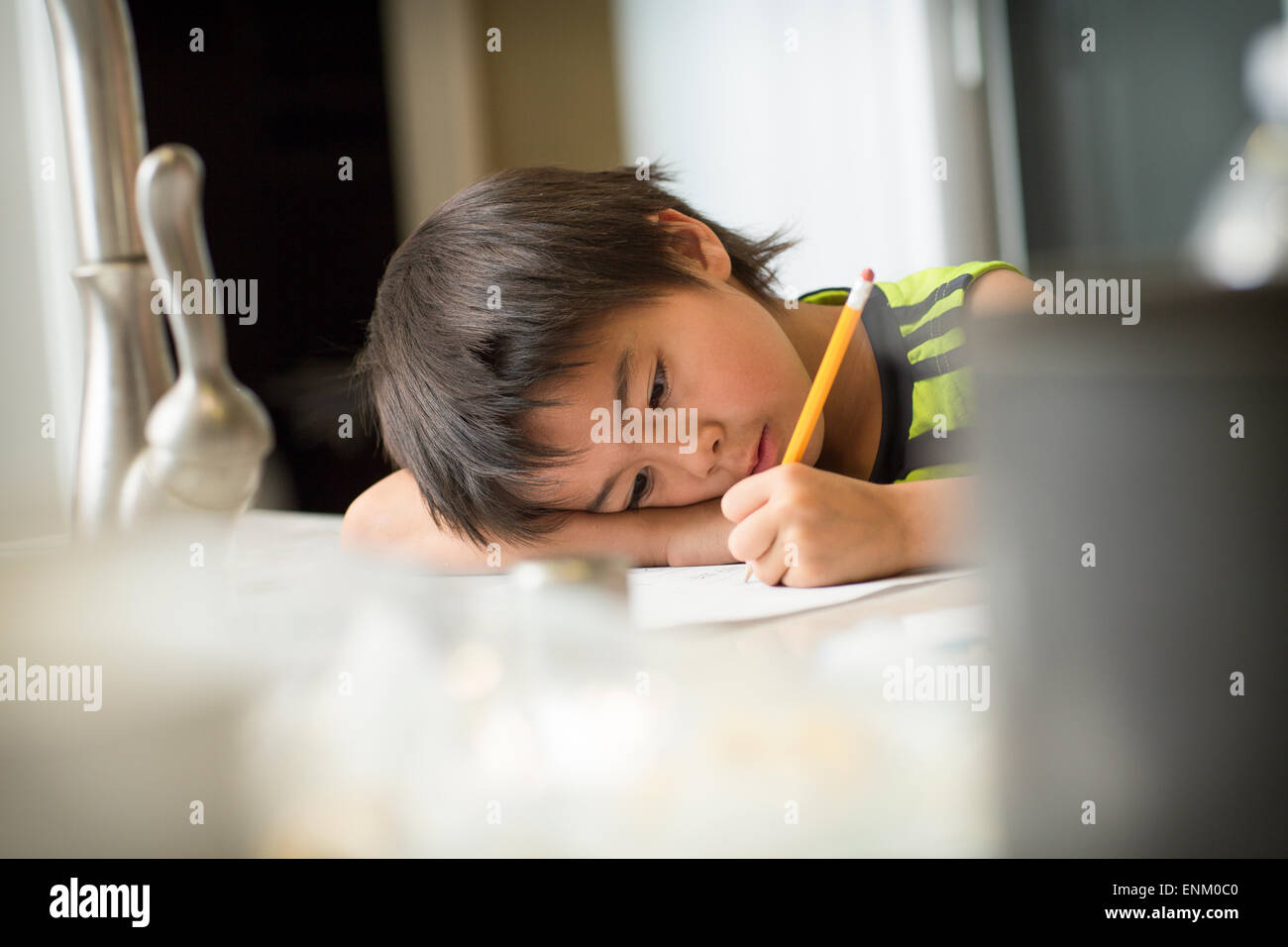 A Japanese boy studies Japanese homework in a kitchen. Stock Photo