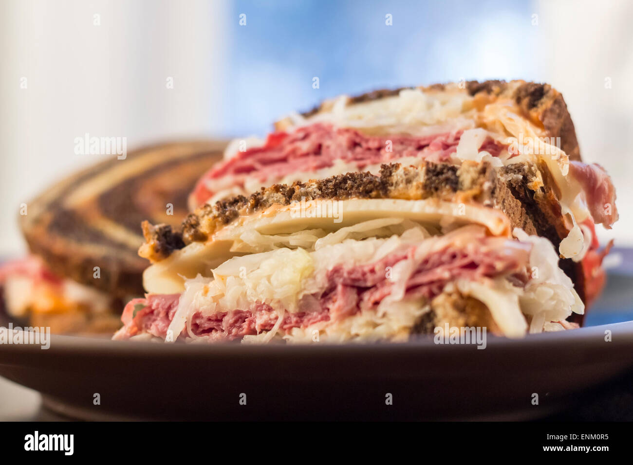 Classic reuben sandwich on pumpernickel swirl rye bread. A hearty meal with a side of pickle and chips Stock Photo