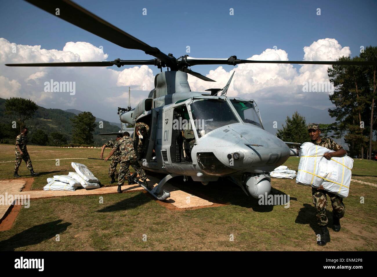 Nepalese military service members unload supplies from a U.S. Marine UH-1Y Huey helicopter during a aid relief mission into remote areas May 5, 2014 in Charikot, Nepal. Stock Photo
