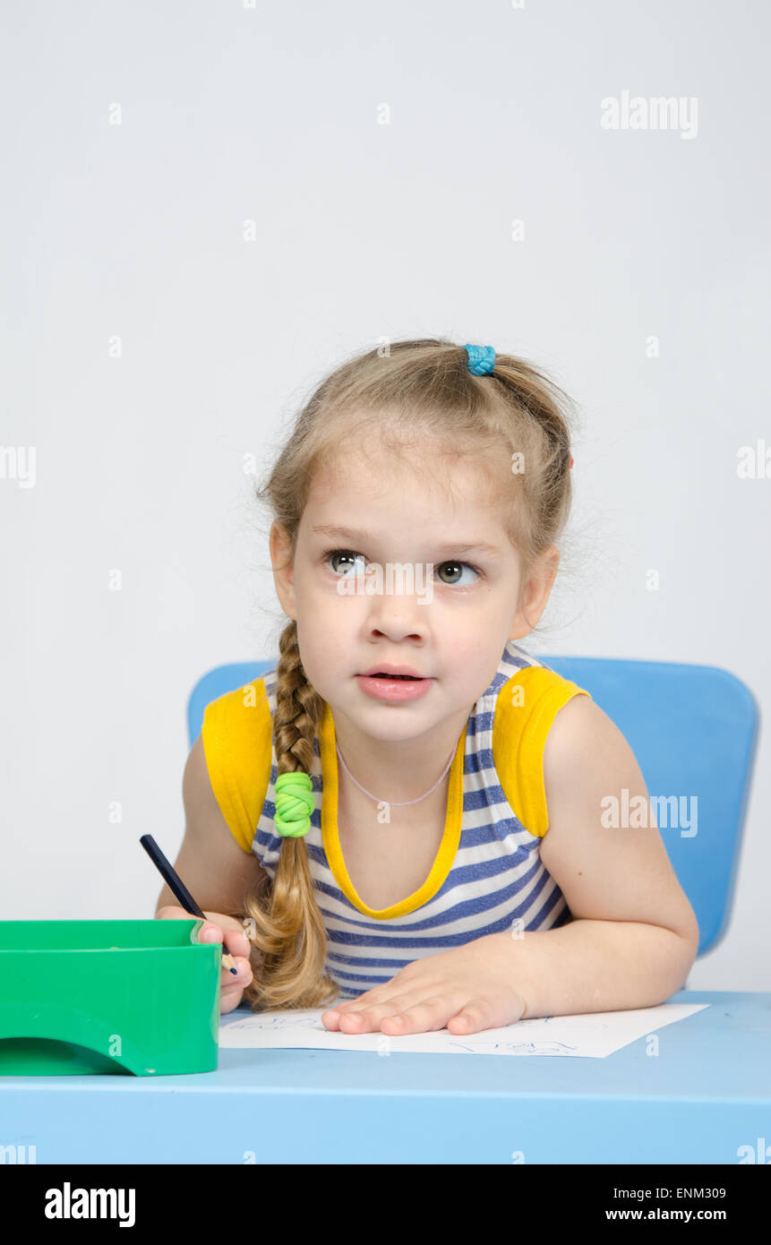Four-year girl Europeans draws pencil on a sheet, sitting at the table Stock Photo