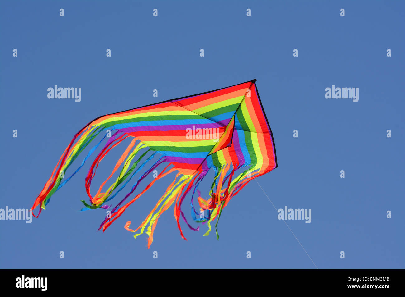 Colourful Kite Hovers in blue sky Stock Photo