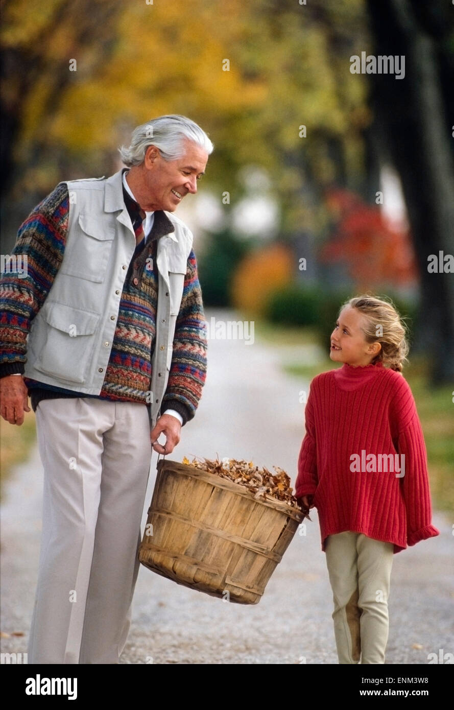 grandfather and granddaughter enjoying carrying basket of leaves Stock Photo