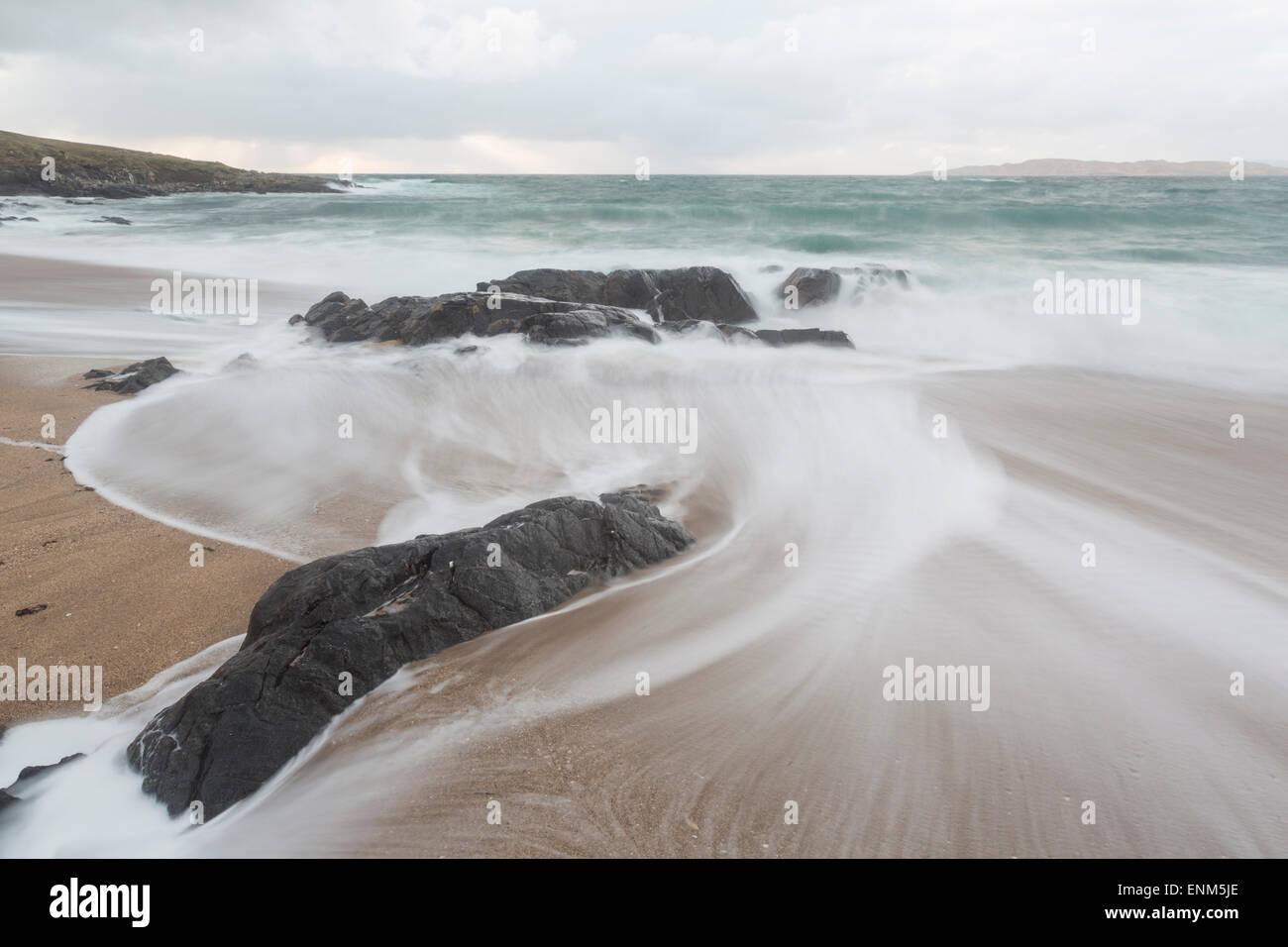 A long exposure of tides circling rocks on a beach in Harris Stock Photo